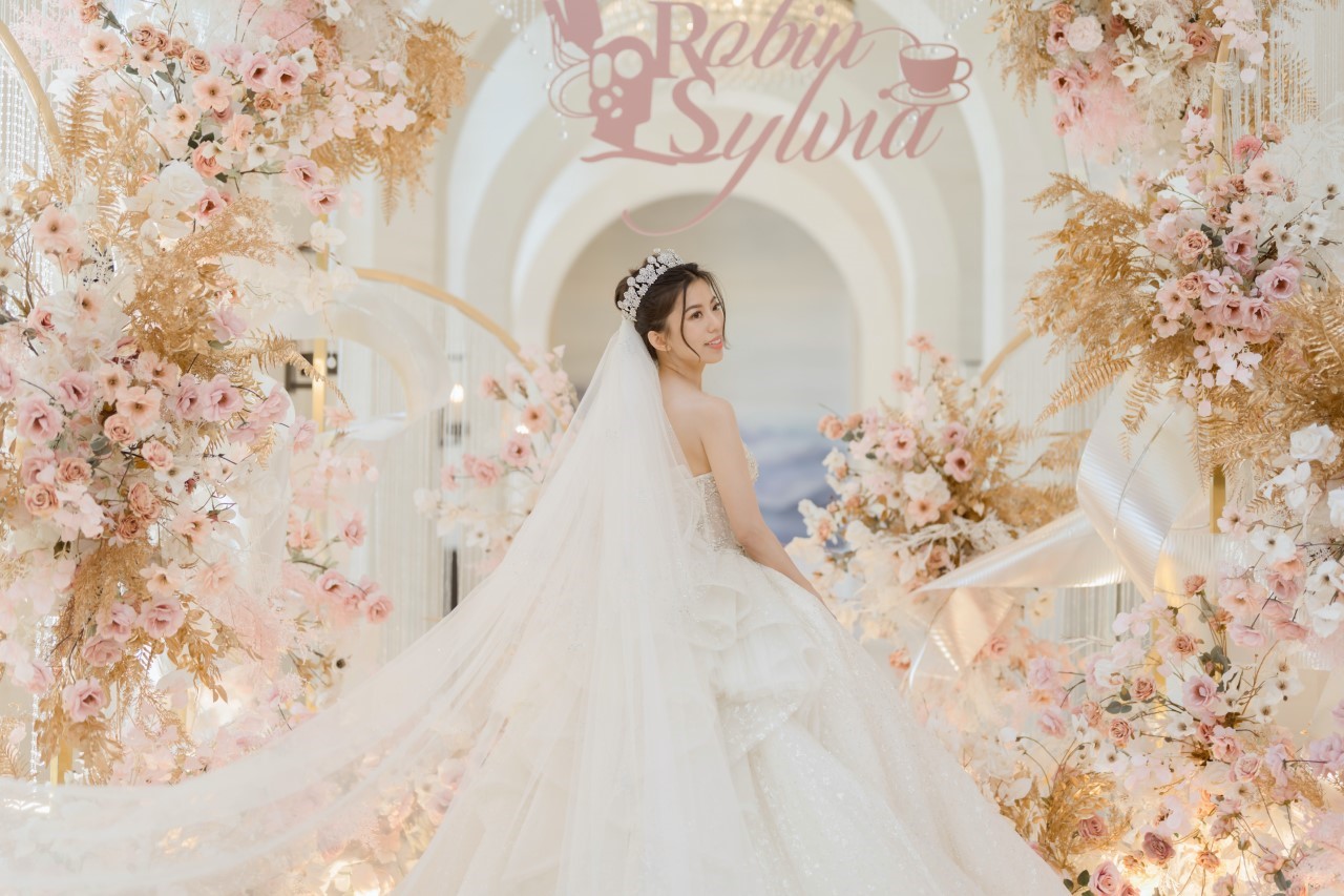 新娘在浪漫粉色花朵拱門前身穿白紗