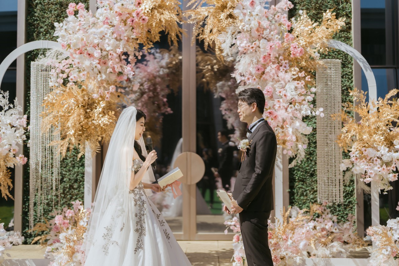 新娘在花朵拱門前對新郎念誓詞