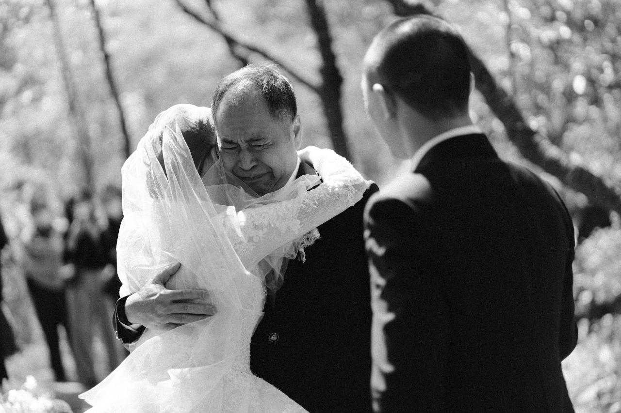新娘和父親擁抱時父親流淚的黑白照片